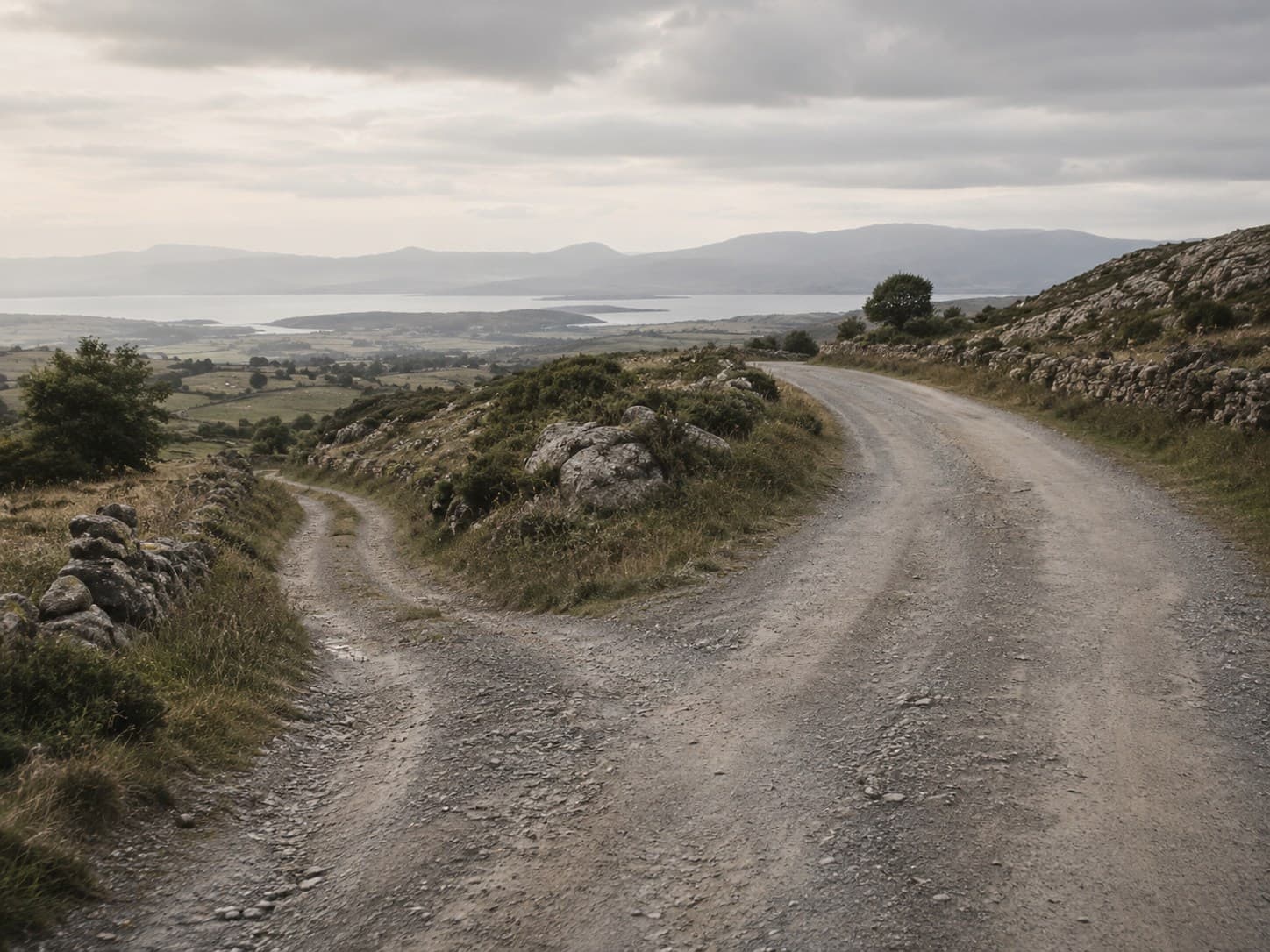 Uma estrada de terra batida a bifurcar-se em dois percursos possíveis, numa paisagem aberta